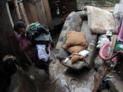Un mujer trata de rescatar sus pertenenecias de una casa inundada. REUTERS  /