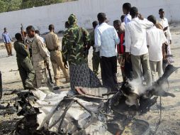 Un grupo de viandantes curiosea junto a los restos del coche bomba. EFE  /