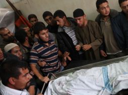 Palestinos rodean el cuerpo sin vida de un militante palestino de Yihad islámica en el ataque aéreo israelí. AFP  /