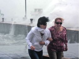 Dos mujeres buscan resguardo del fuerte oleaje en el puerto de Veracruz. EL UNIVERSAL  /
