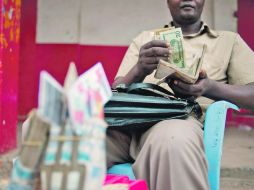 Un hombre cuenta los dólares que ha recibido por la mercancía que logró intercambiar, en El Congo. AFP  /