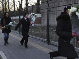 Varias mujeres llevan ramos de flores a la embajada de Corea del Norte en Pekín como muestra de duelo por la muerte del líder. EFE  /