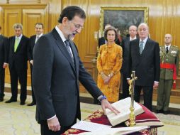 Con una mano sobre la Biblia, el nuevo presidente español jura al cargo en La Zarzuela, ante el rey Juan Carlos I y la reina Sofía. EFE  /