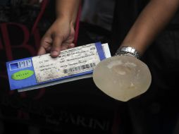 Una mujer muestra un certificado y un implante de seno de la marca francesa PIP, en Caracas.AFP  /