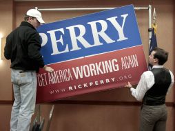 Colaboradores de la campaña de  Rick Perry retiran el letrero de campaña. AP  /