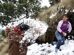 Un grupo de personas se divierten arrojandose nieve  en las faldas del volcán Popocatepetl . EFE  /