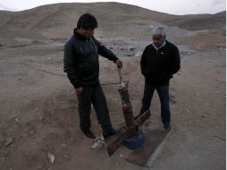 Dos mineros que sobrevivieron al accidente de 2010 muestran la sonda a través de la que recibían alimentos. ARCHIVO  /