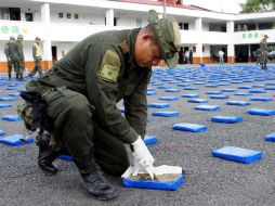 Un miembro de esa fuerza inspecciona la marihuana y cocaína decomisadas. EFE  /
