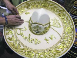 Artesanos colocan los adornos a un sombrero charro con el nombre del jefe del Vaticano. AP  /