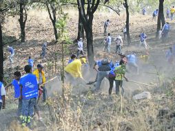 Una brigada realiza labores de limpieza para remover material combustible y basura en La Primavera.  /