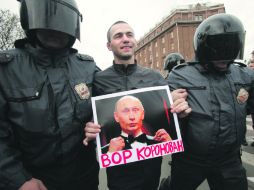 La Policía retiene a un manifestante contra la asunción al poder de Putin. “El ladrón ha sido coronado”, dice el cartel. AP  /