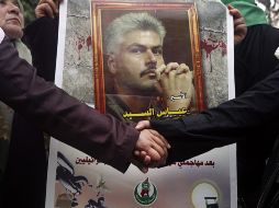 Mujeres palestinas se dan la mano junto a una foto de un familiar en una protesta para pedir la liberación de presos palestinos. EFE  /