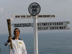 El navegante británico Ben Ainslie muestra la Antorcha Olímpica en el punto donde comenzó oficialmente el recorrido de la flama. EFE  /