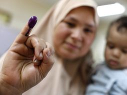 Una mujer acude a votar con su hijo en brazos. AP  /