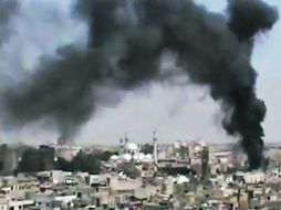 Una columa de humo brota de un edificio en la ciudad de Homs, tras un bombardeo de las fuerzas sirias.  AP  /