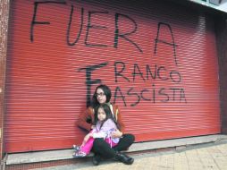 Una mujer y una niña permanecen sentadas al pie de una cortina con una leyenda en repudio al  presidente Federico Franco. REUTERS  /