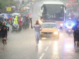 Bajo una lluvia torrencial, el atleta Glenn Chambers lleva la antorcha olímpica hacia Londres. AP  /