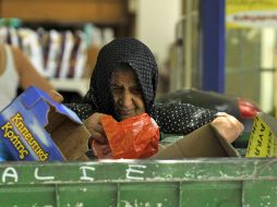 Una anciana griega busca comida entre la basura de un centro comercial en Tesalonia. AP  /