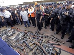 Agentes de la policía custodian tras la entrega simbólica de al menos 87 armas de fuego, algunas deterioradas y hasta sin gatillo. EFE  /