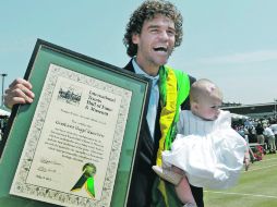 Gustavo Kuerten sostiene a su hija de cinco meses y la placa que lo conmemora como miembro del Salón de la Fama del Tenis. AP  /