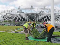 A chambear. Los equipos de una de las constructoras instalan un pedazo de pasto a un costado del Estadio Olímpico. AP  /