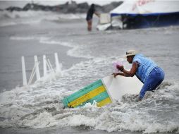 Una mujer trata de recuperar un mueble de playa arrastrado por el mar, en Veracruz. REUTERS  /