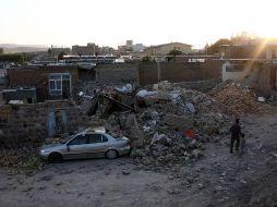 Un hombre y su hijo iraní caminan frente a las casas devastadas por los sismos. AFP  /