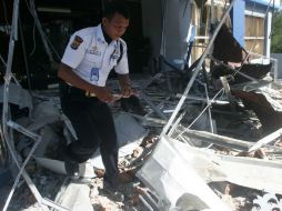 Un oficial registra una casa que colpasó a causa del movimiento telúrico en la isla de Sulawesi. ARCHIVO  /