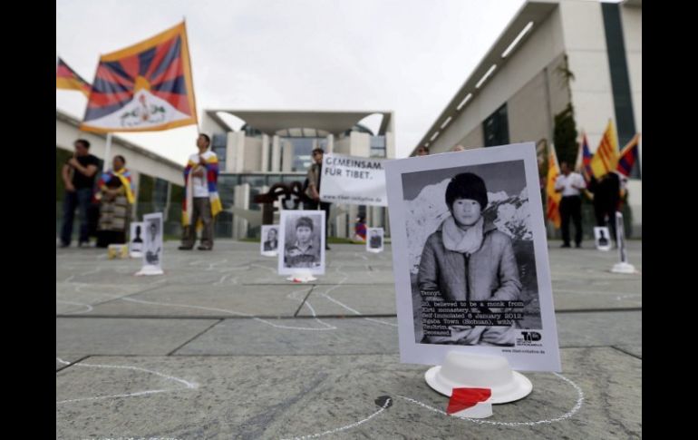 Varias personas se manifiestan junto a los retratos de las personas, que han muerto tras prenderse fuego como protesta política. EFE  /
