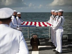 Marinos portan una bandera de Estados Unidos sobre los restos del astronauta Neil Armstrong. AP  /
