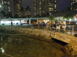 Los visitantes y residentes de Oahu ver el nivel de agua en el puerto de Ala Wai esperando la llegada de un tsunami. AP  /