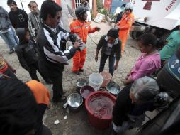 La gente recibe agua de voluntarios. ARCHIVO  /