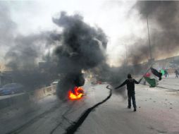 Palestinos lanzan piedras, mientras el fuego consume  llantas, en Gaza, cerca de Ramallah. REUTERS  /
