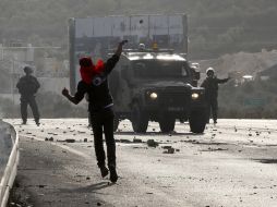 Un manifestante palestino lanza piedras a un vehículo militar israelí. REUTERS  /