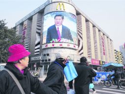 Contrastes. El nuevo dirigente del comunismo chino, Xi Jinping, aparece en una pantalla debajo de un icono del capitalismo. EFE  /