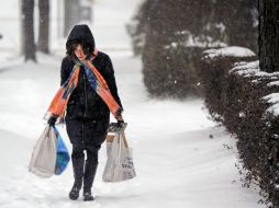 Una mujer camina sobre la nieve tras hacer sus compras. XINHUA  /