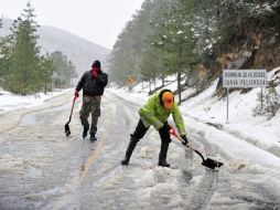 Elementos de Protección Civil limpian hoy una carretera en la Sierra de Arteaga, en Coahuila, donde cayó una nevada. EFE EFE /