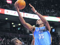 La figura. Kevin Durant intenta lanzar a la canasta, eludiendo la marca de Amir Johnson, jugador de los Raptors. EFE /