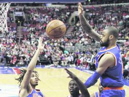 En tierra de gigantes. Jrue Holiday (11) dispara a la canasta ante la marca de Chris Copeland (14) y Tyson Chandler. AP /