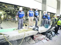 Elementos de la Marina observan un muro caído en uno de los pasillos del edificio B de la Torre de Pemex. AFP /