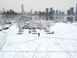 Un hombre carga a un niño en un parque cubierto de nieve hoy, en Nanjing, China. AP /