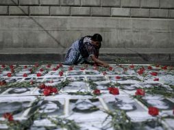 Una mujer coloca unas rosas sobre imágenes de víctimas del conflicto armado. EFE /