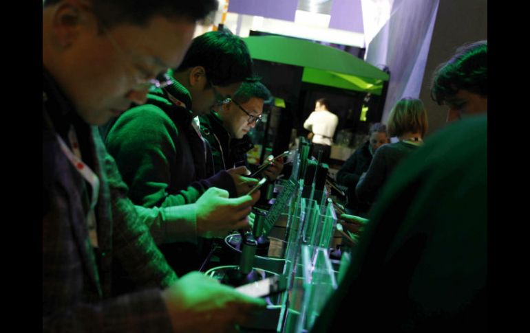 Varias personas manipulan los nuevos equipos de telefonía celular durante el Congreso Anual de Telefonía Móvil. EFE /