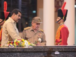 Acompañado por Maduro, Castro hace un saludo militar frente a la tumba Chávez, sobre la que deposita una flor blanca. EFE /