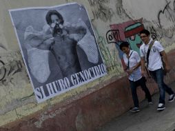 Dos jóvenes caminan frente a un cartel en el que se lee ''Sí hubo genocidio'' en una de las calles del centro histórico de Guatemala. EFE /