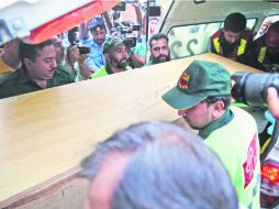 Inusual. Rescatistas bajan uno de los féretros de la ambulancia. AFP /