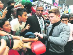 Saúl Álvarez firma unos guantes; el jalisciense fue el más vitoreado por los aficionados que se dieron cita en Times Square. AP /