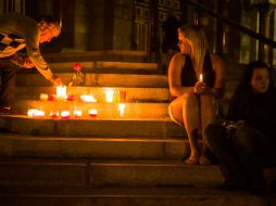 Unas personas encienden velas para recordar a las víctimas mortales del accidente. AFP /