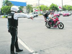 En la zona de la glorieta Niños Héroes, un oficial de vialidad detiene a un motociclista que transitaba sin casco.  /