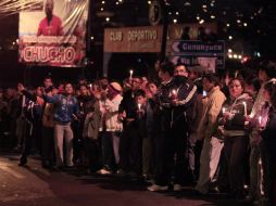 Afuera del Club Deportivo, cientos de personas con veladoras y mantas esperando ver el féretro del jugador. AP /